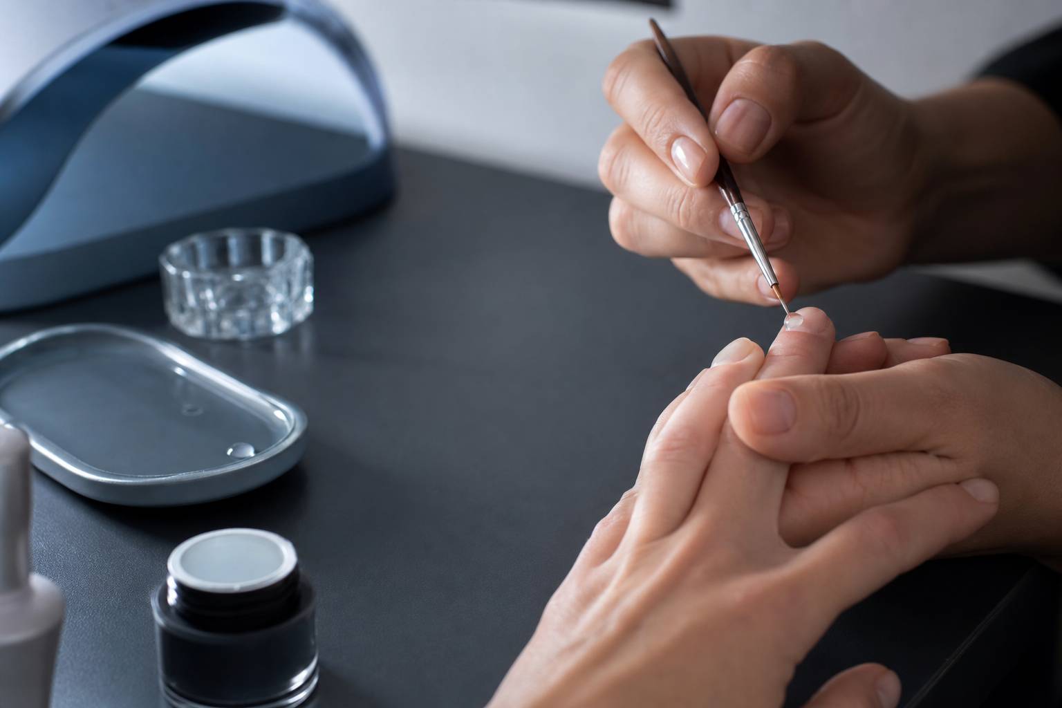 Gros plan sur la pose de résine sur ongle avec pinceau fin en atelier